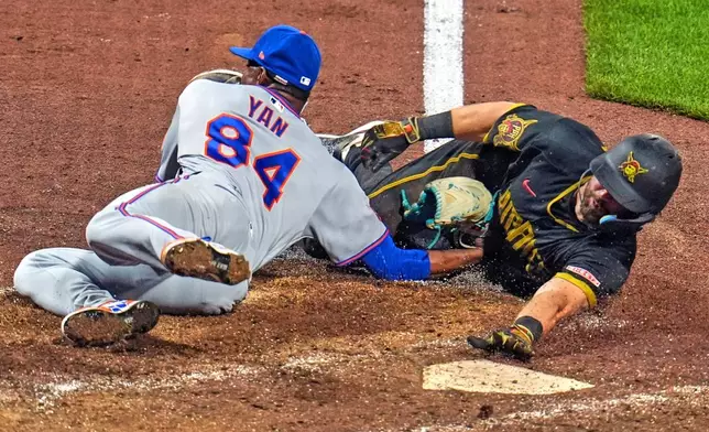 New York Mets pitcher Jefry Yan (84) tags out Pittsburgh Pirates' Jared Triolo who was attempting to score on a wild pitch during the seventh inning of a baseball game in Pittsburgh, Friday, Aug. 7, 2026. (AP Photo/Gene J. Puskar)