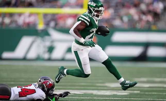 New York Jets running back Breece Hall (20) runs from Tampa Bay Buccaneers cornerback Ayden Garnes, left, during the first half of a preseason NFL football game, Friday, Aug. 14, 2026, in East Rutherford, N.J. (AP Photo/Frank Franklin II)