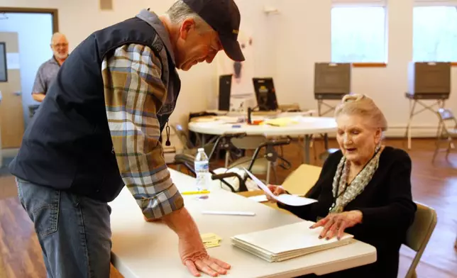 Sen. Dan Sullivan, R-Alaska, receives his ballot from poll worker Jo Ann Johnson to vote in the primary election, at his precinct located at the Alaska Zoo in Anchorage, Alaska., Tuesday, Aug. 18, 2026. (AP Photo/Mark Thiessen)
