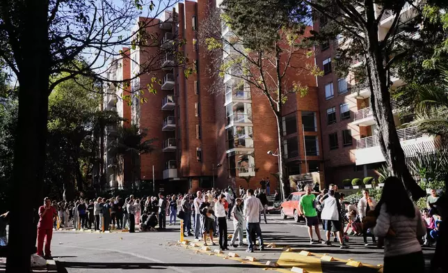 People stand outside their homes after a quake was felt in Bogota, Colombia, Monday, Aug. 10, 2026. (AP Photo/Ivan Valencia)