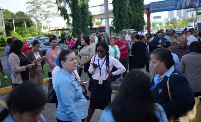 Government workers stand outside their office buildings in Panama City, Monday, Aug. 10, 2026, after feeling an earthquake with an epicenter in neighboring Colombia. (AP Photo/Matias Delacroix)