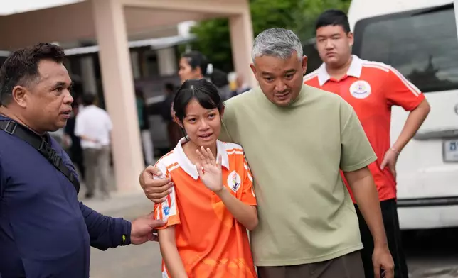 A student is guided away from the scene after a shooting at the Debsirin Nonthaburi School in Thailand's Nonthaburi province, Friday, Aug. 7, 2026. (AP Photo/Sakchai Lalit)