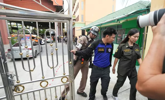 Security officers stand at the gate of a school where deaths and injuries were reported after a shooting in Thailand's Nonthaburi province, Friday, Aug. 7, 2026. (AP Photo/Sakchai Lalit)