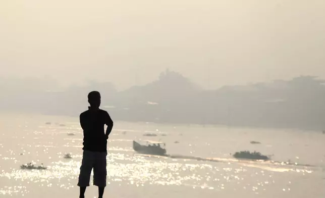 A man is silhouetted against the haze from wildfires that blankets Musi River in Palembang, South Sumatra, Indonesia, Sunday, Aug. 23, 2026. (AP Photo/Muhammad Fajri)