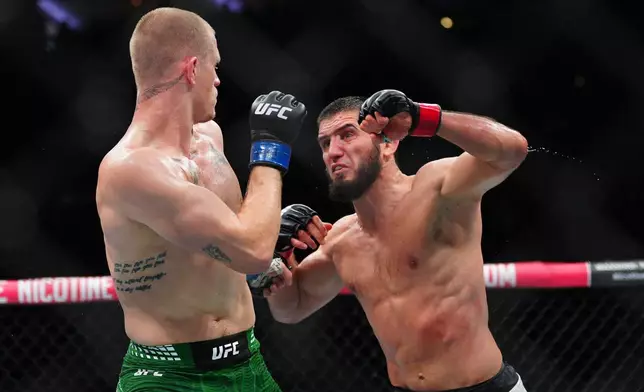 Islam Makhachev, right, punches Ian Machado Garry in a welterweight title fight at the UFC 330 mixed martial arts event Sunday, Aug. 16, 2026, in Philadelphia. (AP Photo/Derik Hamilton)