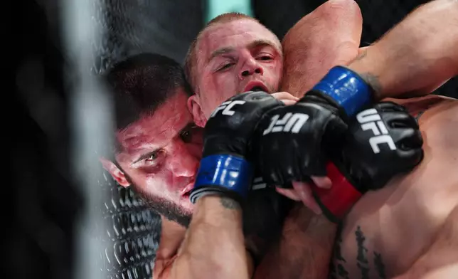 Islam Makhachev, left, and Ian Machado Garry battle in a welterweight title fight at the UFC 330 mixed martial arts event Sunday, Aug. 16, 2026, in Philadelphia. (AP Photo/Derik Hamilton)