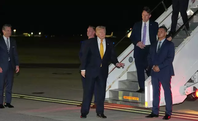 As Defense Secretary Pete Hegseth watches at left, President Donald Trump gestures as he switches planes at U.S. Air Force Base, RAF Mildenhall in Suffolk Eastern England, on his way back to Washington from the NATO summit in Ankara, Turkey, Wednesday, July 8, 2026. (AP Photo/Alex Brandon)