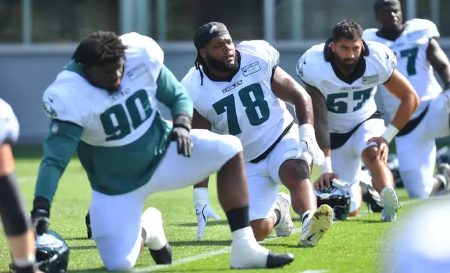 Philadelphia Eagles defensive tackle Jordan Davis (90), offensive lineman Myles Hinton (78) and outside linebacker A.J. Epenesa (57) warm up with teammates during a joint NFL football practice with the New England Patriots, Wednesday, Aug. 19, 2026, in Foxborough, Mass. (AP Photo/Steven Senne)