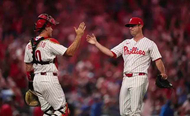 Philadelphia Phillies pitcher Brooks Raley, right, and catcher J.T. Realmuto celebrate after the Phillies won a baseball game against the Miami Marlins, Tuesday, Aug. 18, 2026, in Philadelphia. (AP Photo/Matt Rourke)