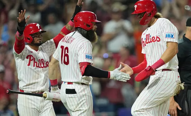 Philadelphia Phillies' Luis Arraez, left, and Alec Bohm, right, celebrate with Brandon Marsh (16) after scoring of an RBI double hit by Phillies Bryson Stott during the sixth inning of a baseball game against the Miami Marlins,Tuesday, Aug. 18, 2026, in Philadelphia. (AP Photo/Matt Rourke)