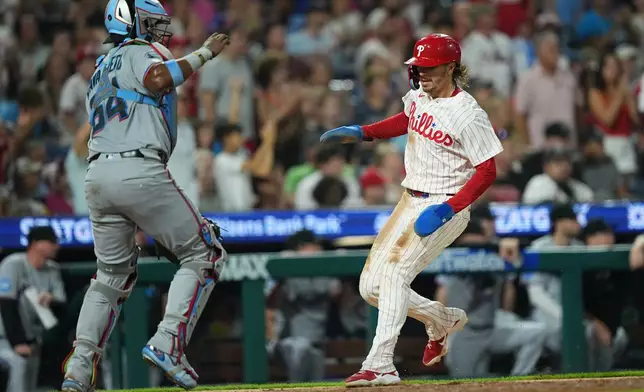 Philadelphia Phillies' Bryson Stott, scores past Miami Marlins catcher Brian Navarreto, on an RBI single by Kyle Schwarber, during the eighth inning of a baseball game, Tuesday, Aug. 18, 2026, in Philadelphia. (AP Photo/Matt Rourke)