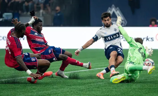 Vancouver Whitecaps' Brian White (24) scores on FC Dallas goalkeeper Jonathan Sirois (40) as FC Dallas' Sebastien Ibeagha, left, and Lalas Abubakar (5) defend during the first half of an MLS soccer match in Vancouver, British Columbia, Saturday, Aug. 22, 2026. (Ethan Cairns/The Canadian Press via AP)