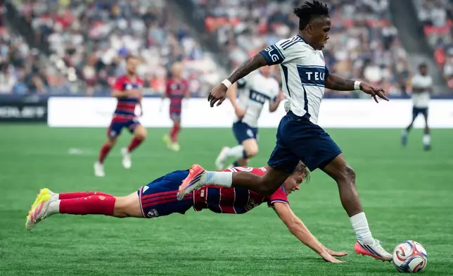 Vancouver Whitecaps' Edier Ocampo, right runs with the ball as FC Dallas' Nolan Norris dives during the first half of an MLS soccer match in Vancouver, British Columbia, Saturday, Aug. 22, 2026. (Ethan Cairns/The Canadian Press via AP)