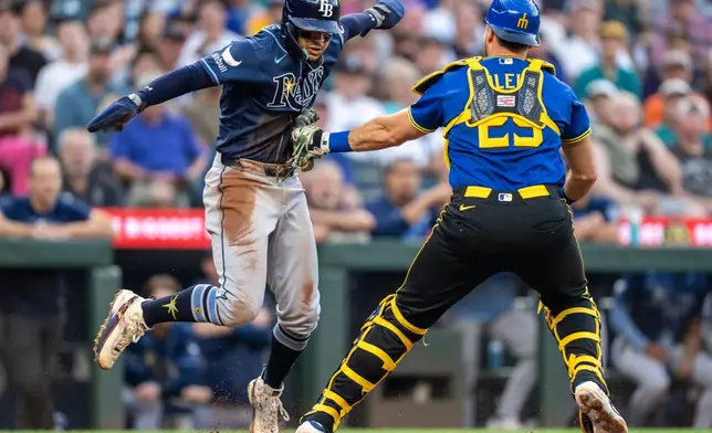 Seattle Mariners catcher Cal Raleigh, right, tags out Tampa Bay Rays' Victor Mesa Jr., left, during the fifth inning of a baseball game, Friday, Aug. 7, 2026, in Seattle. (AP Photo/Stephen Brashear)