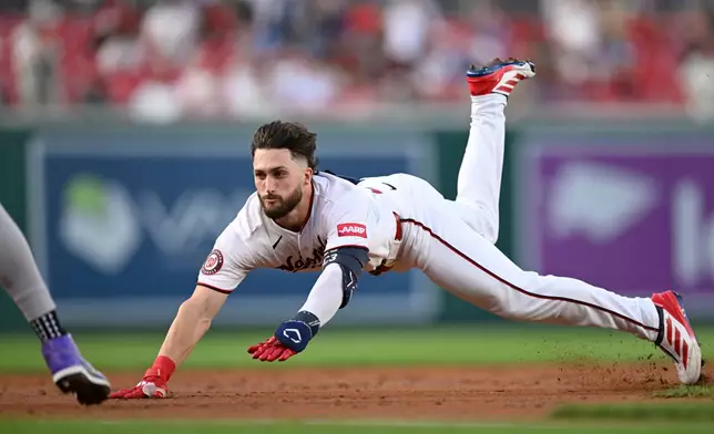 Washington Nationals' Dylan Crews dives into third base for a triple during the first inning of a baseball game against the Colorado Rockies, Wednesday, Aug. 26, 2026, in Washington. (AP Photo/John McDonnell)