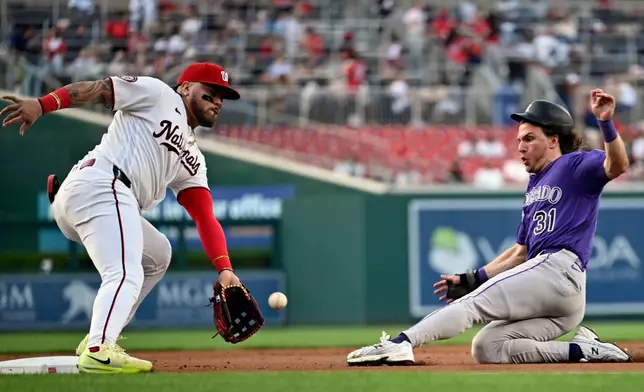 Colorado Rockies' Jake McCarthy beats the throw to Washington Nationals third baseman Andrés Chaparro for a steal during the first inning of a baseball game, Wednesday, Aug. 26, 2026, in Washington. (AP Photo/John McDonnell)