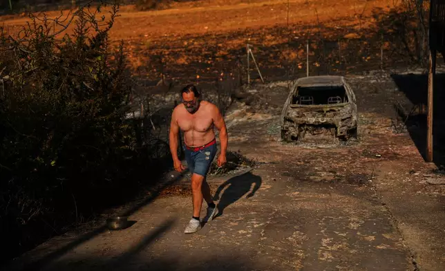 Julian Alonso walks on his property destroyed by a wildfire in El Encinar del Alberche, Madrid province, Spain, Thursday, July 30, 2026. (AP Photo/Manu Fernandez)