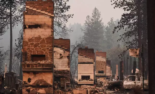 Chimneys are the only structures remaining in a residential neighborhood after a wildfire hit the northern part of Spokane, Wash., Monday, Aug. 3, 2026. (AP Photo/Lindsey Wasson)