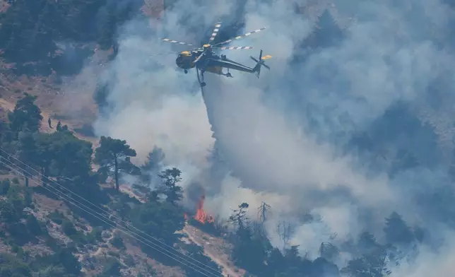 A firefighting helicopter drops water over a wildfire on Mount Kithairon near Porto Germeno, northwest of Athens, Greece, Monday, Aug. 3, 2026. (AP Photo/Petros Giannakouris)