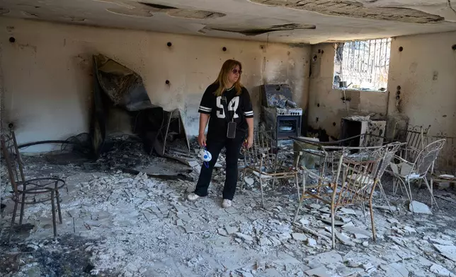 Charoula Spanou stands inside the remains of her holiday home destroyed by a wildfire in Porto Germeno, northwest of Athens, Greece, Tuesday, Aug. 4, 2026. (AP Photo/Petros Giannakouris)