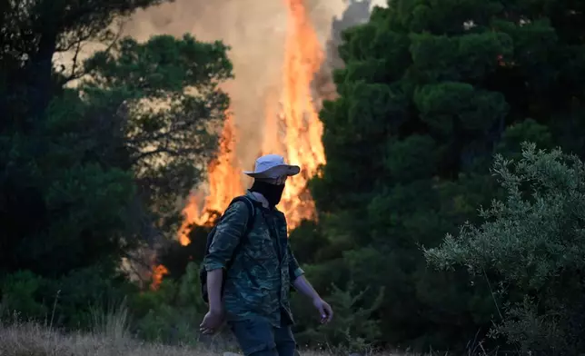 A man watches flames rising during a wildfire near Porto Germeno, northwest of Athens, Greece, Sunday, Aug. 2, 2026. (AP Photo/Michael Varaklas)