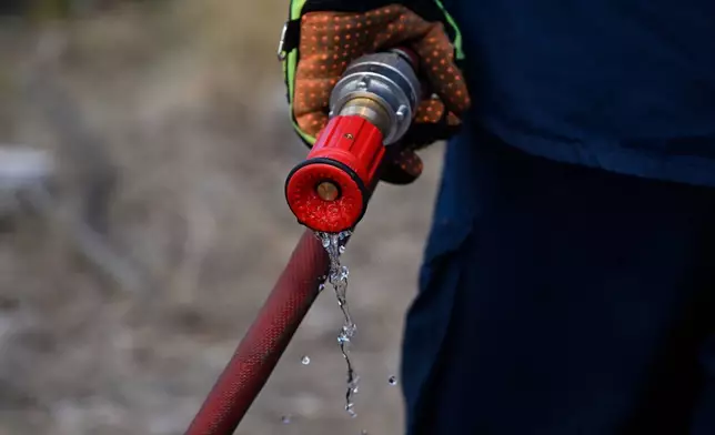 Water drips from a firefighter's hose nozzle during a wildfire near Porto Germeno, northwest of Athens, Greece, Sunday, Aug. 2, 2026. (AP Photo/Michael Varaklas)