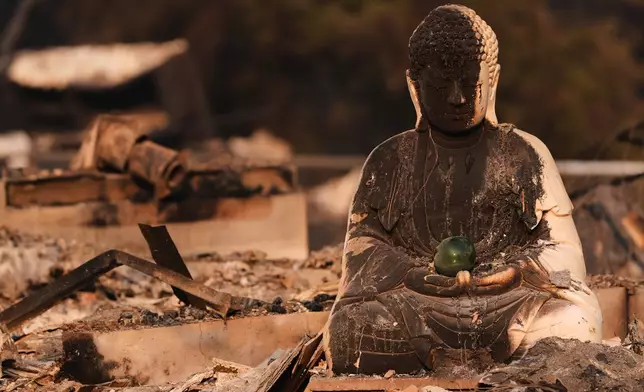 A Buddha statue is seen with fire damage amongst the rubble of a house burned after a wildfire hit the northern part of Spokane, Wash., Monday, Aug. 3, 2026. (AP Photo/Lindsey Wasson)