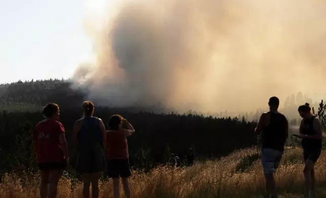 People watch Old Trails Fire from W. Northwest Blvd., Saturday, Aug. 1, 2026, in Spokane, Wash. (AP Photo/Young Kwak)