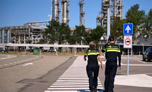 Police officers walk to a refinery and fuel terminal run by Gunvor Energy after an explosion at the Dutch port of Rotterdam which killed at least one person and injured several others according to police, in Rotterdam, Netherlands, Thursday, Aug. 13, 2026. (AP Photo/Mouneb Taim)