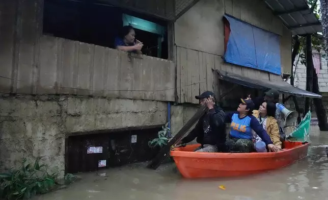 Police Lt. Col. Rowena Amata, second from left, and village officials, on boat, remind a resident to evacuate to higher grounds as floodwaters caused by heavy seasonal monsoon rains inundate a village at Bagong Silangan in Quezon city, Metro Manila, Philippines Monday, Aug. 10, 2026. (AP Photo/Aaron Favila) CORRECTION: Corrects typo in location to Silangan, instead of Silagan