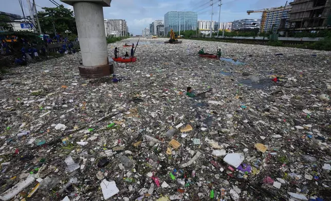 Workers try to clear a sea of garbage and debris brought by intense monsoon rains at the Redemptorist Water Channel in Paranaque city, Metro Manila, Philippines on Tuesday, Aug. 11, 2026. (AP Photo/Aaron Favila)