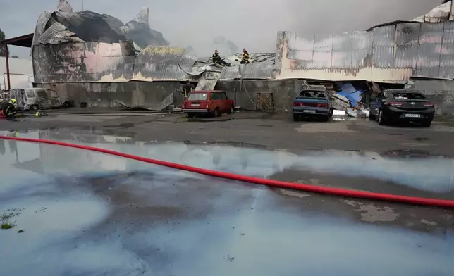 Firefighters put out a fire with spilled milk in the foreground after Russian missiles hit a food warehouse near Kyiv, Ukraine, Wednesday, Aug. 5, 2026. (AP Photo/Efrem Lukatsky)