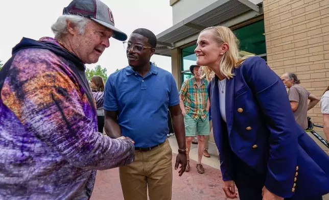 Democratic gubernatorial nominee David Crowley, center, and lieutenant governor nominee Sarah Godlewski, right, meet supporter Mike Balisle, left, following a breakfast with Democratic leaders Wednesday, Aug. 12, 2026, in Middleton, Wis. (AP Photo/Kayla Wolf)