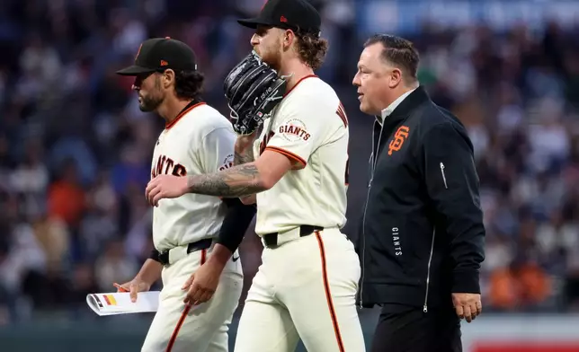 San Francisco Giants pitcher Carson Whisenhunt, center, walks off the mound with manager Tony Vitello, left, and Dave Groeschner, vice president of medical & performance, during the third inning of a baseball game against the Cincinnati Reds in San Francisco, Monday, Aug. 24, 2026. (AP Photo/Jed Jacobsohn)