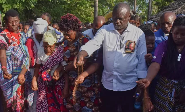 Nixon Charo, father of 29 years old Penina Zawadi, who died from complications while giving birth, casts a handful of soil into her grave during her funeral in Kilifi County, Kenya, Saturday, July 18, 2026. (AP Photo/Brian Wachira)