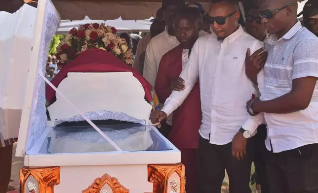 Adams Kahindi, center, mourns beside the coffin of his wife, Penina Zawadi, who died from complications related to childbirth, in Kilifi County, Kenya, Saturday, July 18, 2026. (AP Photo/Brian Wachira)