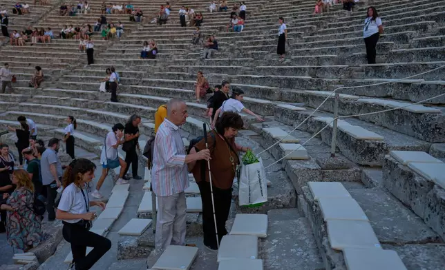 A visually impaired theatergoer and his companion make their way to their seats before a performance of Euripides' tragedy The Trojan Women, staged by the National Theatre of Greece at the Ancient Theater of Epidaurus on Sunday, Aug. 2, 2026. (AP Photo/Petros Giannakouris)