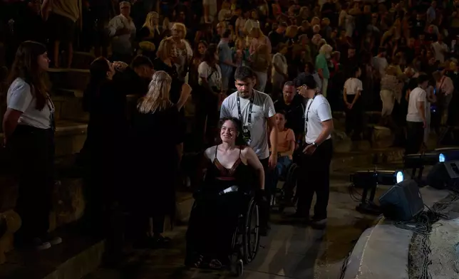 Oltjana Zoupas, an artist who uses a wheelchair, leaves the Ancient Theater of Epidaurus after attending a performance of Euripides' tragedy The Trojan Women, staged by the National Theatre of Greece, in Epidaurus, Greece, on Sunday, Aug. 2, 2026. (AP Photo/Petros Giannakouris)