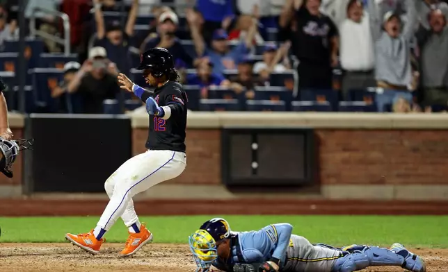 New York Mets' Francisco Lindor scores the winning run past Milwaukee Brewers catcher William Contreras during the 10th inning of a baseball game on Tuesday, Aug. 25, 2026, in New York. (AP Photo/Adam Hunger)