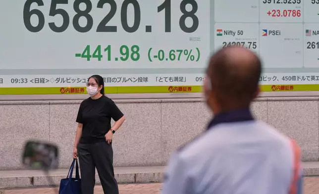 People stand near an electronic stock board showing Japan's Nikkei index at a securities firm Thursday, Aug. 27, 2026, in Tokyo. (AP Photo/Eugene Hoshiko)