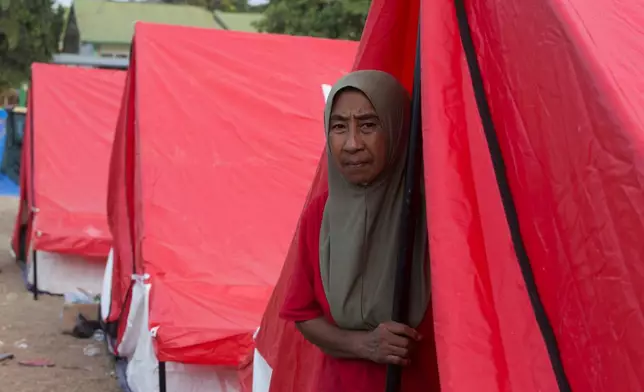 A woman looks out from at a temporary shelter for earthquake survivors in Reo, East Nusa Tenggara province, Indonesia, Monday, Aug. 17, 2026. (AP Photo/Firdia Lisnawati)