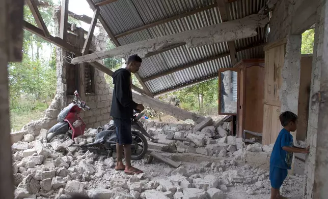 Saverinus Serli, left, inspects his earthquake-damaged house in Lelak, East Nusa Tenggara province, Indonesia, Sunday, Aug. 16, 2026. (AP Photo/Firdia Lisnawati)