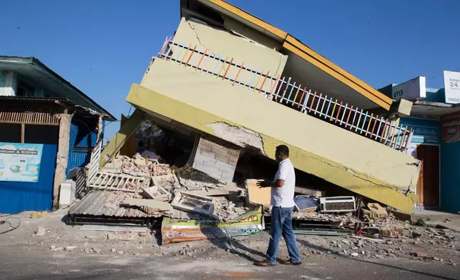 A man walks past a building that collapsed during an earthquake in Reo, East Nusa Tenggara province, Indonesia, Monday, Aug. 17, 2026. (AP Photo/Firdia Lisnawati)