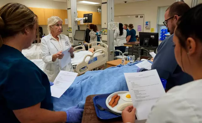Nursing Instructor Sherry Troop, back left, speaks to nursing students in the simulation lab at Forsyth Technical Community College in Winston-Salem, N.C., Thursday, Aug. 20, 2026. (AP Photo/Chuck Burton)