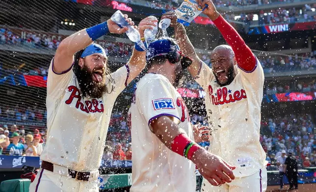 Philadelphia Phillies' Brandon Marsh, left and Bryan De La Cruz, right, douse Kyle Schwarber, center, after a baseball game against the St. Louis Cardinals, Sunday, Aug. 23, 2026, in Philadelphia. (AP Photo/Laurence Kesterson)