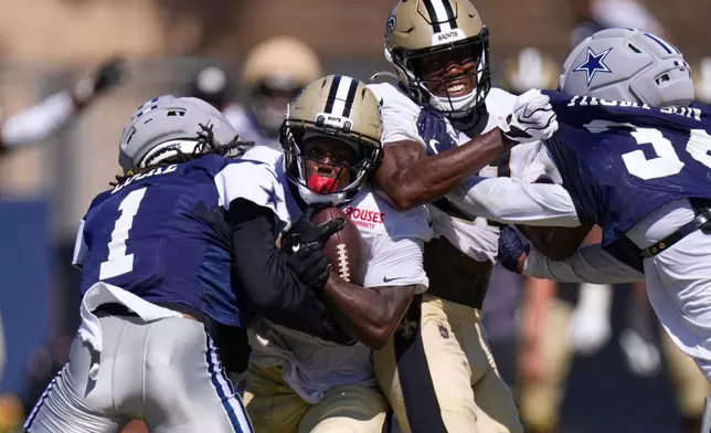 New Orleans Saints running back Travis Etienne, second from left, tries to get by Dallas Cowboys safety P.J. Locke, left, as wide receiver Kevin Austin Jr., second from right, and safety Jalen Thompson battle during an NFL football joint practice, Tuesday, Aug. 18, 2026, in Oxnard, Calif. (AP Photo/Mark J. Terrill)