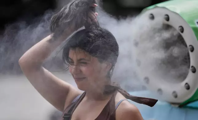 A person cools off at a cooling mist spot on a hot and sunny day at the Sensoji Buddhist temple in Tokyo's Asakusa district, Friday, Aug. 7, 2026. (AP Photo/Eugene Hoshiko)