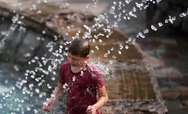 A boy cools himself off in a fountain on a hot summer day in Moscow, Thursday, Aug. 6, 2026. (AP Photo/Pavel Bednyakov)