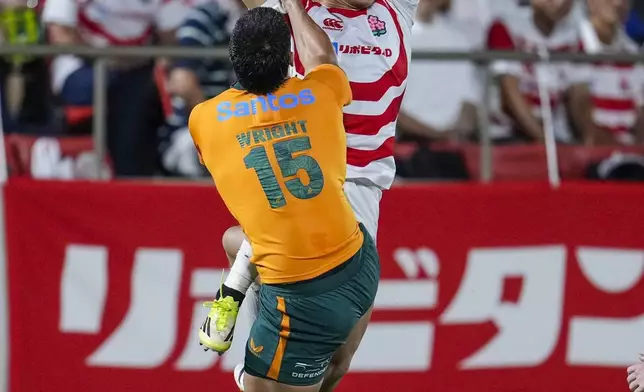 Japan's Kazuma Ueda, back, ties to catch the ball against Australia's Tom Wright during the first half of their rugby match in Higashi Osaka, western Japan, Saturday, Aug. 8, 2026. (Yuki Sato/Kyodo News via AP)