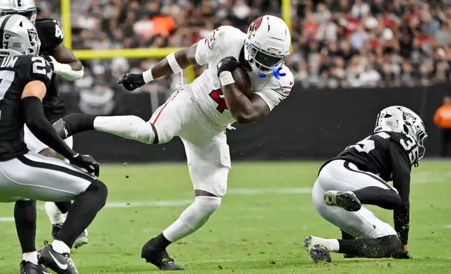 Arizona Cardinals running back Jeremiyah Love (4) runs between Las Vegas Raiders cornerback Hezekiah Masses (35) and Raiders safety Tristin McCollum (27) during the first half of a preseason NFL football game, Thursday, Aug. 13, 2026, in Las Vegas. (AP Photo/David Becker)